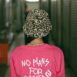 Back view of unrecognizable female teenager in stylish hat and t shirt with No Plans For Summer inscription standing in corridor of modern building