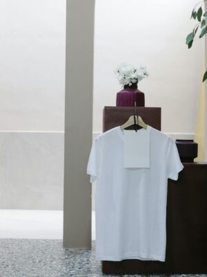 White t shirt with blank label hanging on counter in modern clothes shop